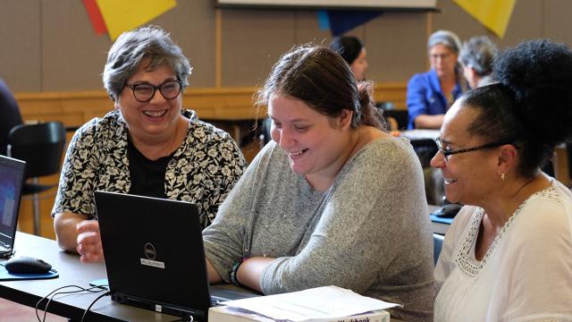 Three people working at a computer