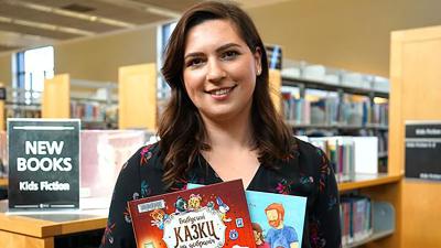 Ukrainian selector holding two Ukrainian kids books in the library