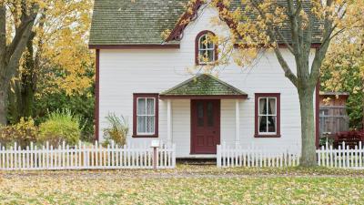 Outside view of a two story house, with a fence in the front and grass