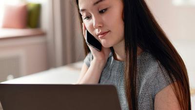 Woman on the phone looking down at her laptop