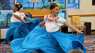 Two women dancing with large flowy skirts inside the library.