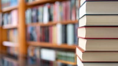 Stack of books in front of bookshelves