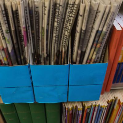 Newspapers stacked together on a bookshelf 