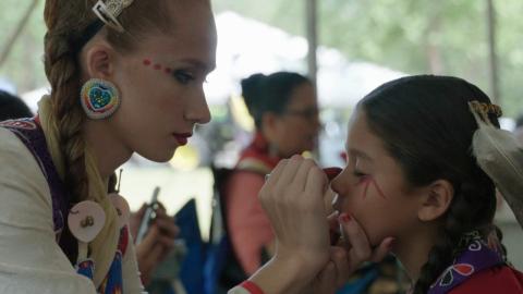 photo of an Indigenous woman painting a girl's face