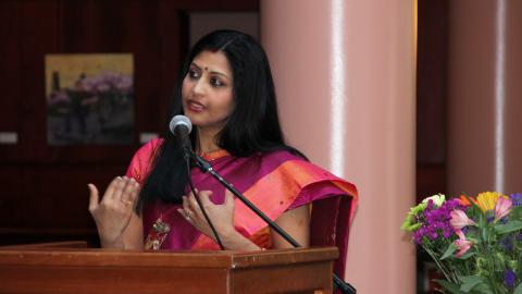 Photo of panel chair Jayanthi Raman speaking at a podium (courtesy of Bindu Malini)