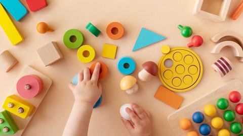 Photo of small hands playing with blocks of many shapes and sizes.