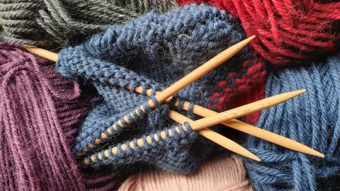 Image of knitting needles among variously colored balls of yarn