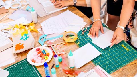 Photo of two people crafting with various materials on a table.