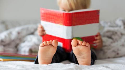 Photo of a child reading a red and white book.