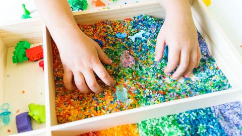 Photo of a child playing with rainbow colored rice