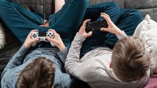 Photo of two young people playing video games on controllers.