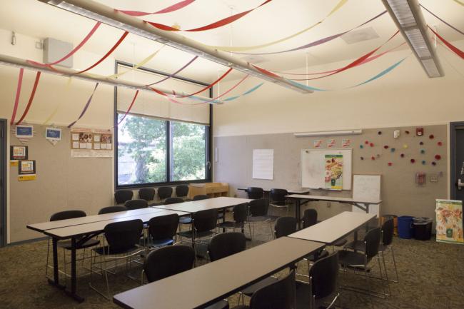 A meeting room with good lighting, long tables, chairs, and a window