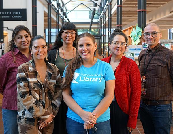 Six members of the Indigenous team inside a library standing with each other smiling