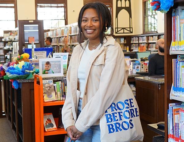 Woman standing inside a library smiling at the camera