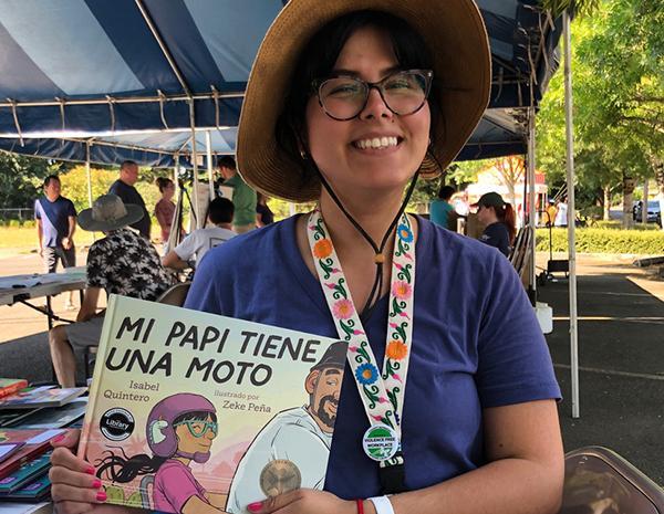 Spanish youth librarian outside holding a book