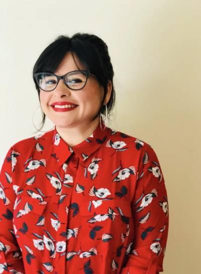 Artist Crystal Meneses smiles at the camera while wearing a red shirt.