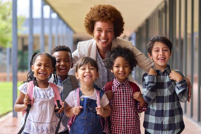 Five smiling kids in front of an adult