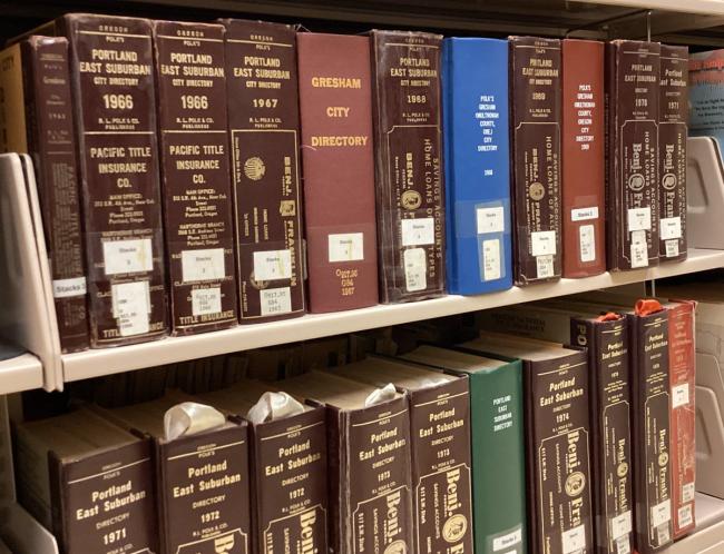 Historical Gresham and Portland East Suburban city directories on a bookshelf at Central Library.