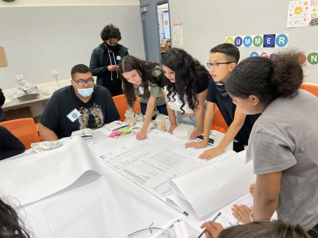 Los adolescentes de East County se reúnen alrededor de una mesa para una actividad de grupo de discusión