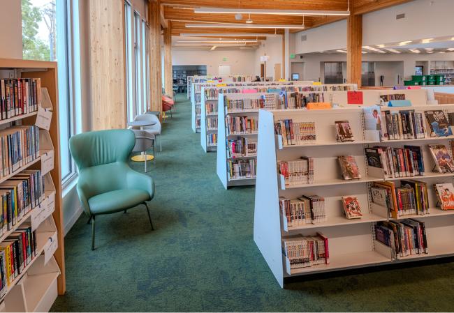 Dentro de la Biblioteca de Holgate, en una gran sala llena de estanterías y asientos junto a las ventanas. 