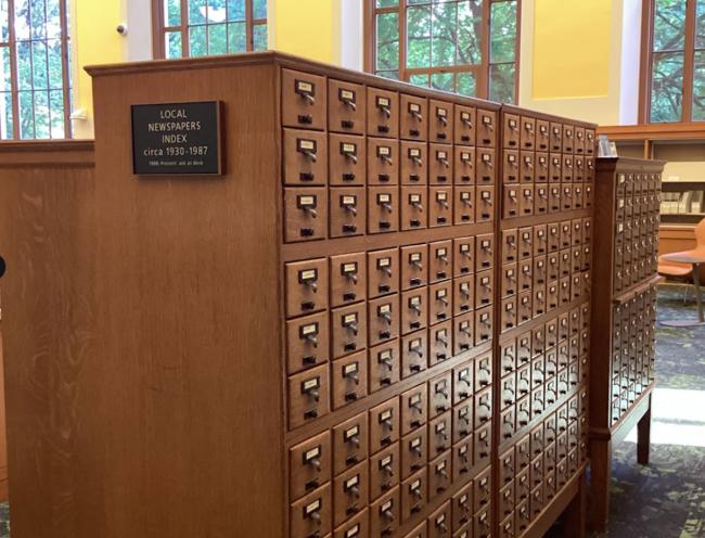 A large piece of furniture with small drawers all throughout known as the local newspaper index card file, located in the Periodicals area at Central Library. 